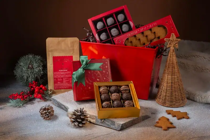 Delicious assorted chocolates and Turkish treats in festive gift boxes with holiday decorations and pinecones, perfect for Christmas gifts from Turkey.