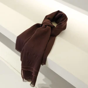 A colorful silk scarf in shades of brown, elegantly draped over a white surface, showcasing Turkish craftsmanship and luxurious fabric quality.