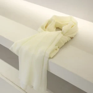 A colorful scarf draped over a white surface, showcasing soft fabric and elegant design.