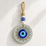 Evil eye wall hanging with jute cord and blue glass beads displayed indoors