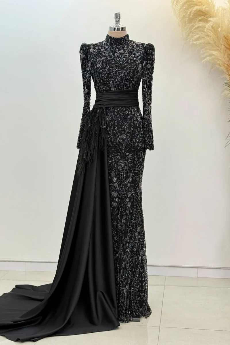 Belvette black hijab evening dress with beaded embroidery, feather trim, sash belt, and trailing skirt on mannequin