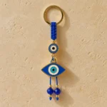 Evil eye keychain clipped to a bag strap showing blue glass beads