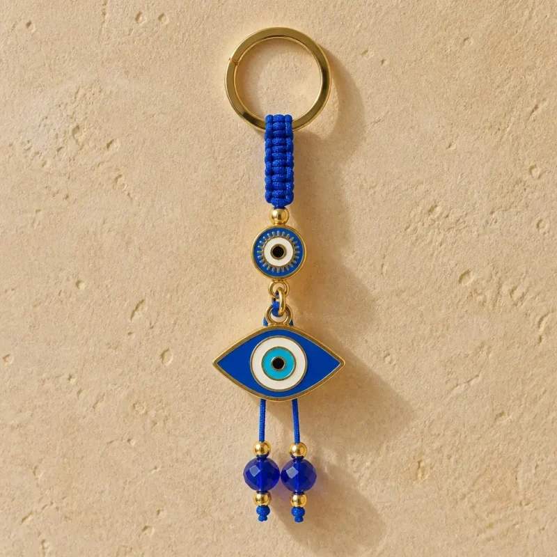 Evil eye keychain clipped to a bag strap showing blue glass beads