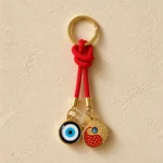 Turkish nazar and pomegranate charm keychain resting on wooden surface