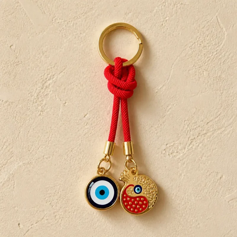 Turkish nazar and pomegranate charm keychain resting on wooden surface