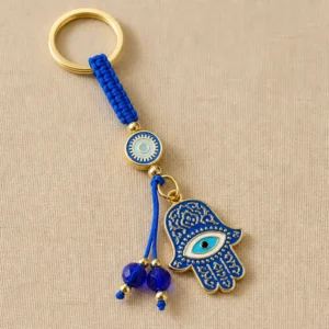 Hamsa evil eye keychain with blue beads on dark textured surface