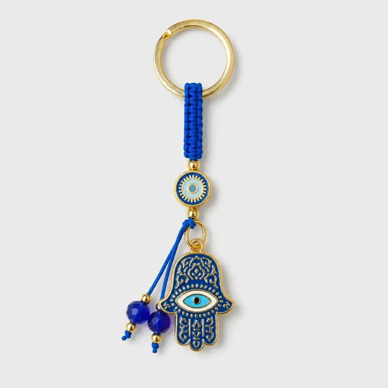 Hamsa evil eye keychain with blue macramé cord held in palm